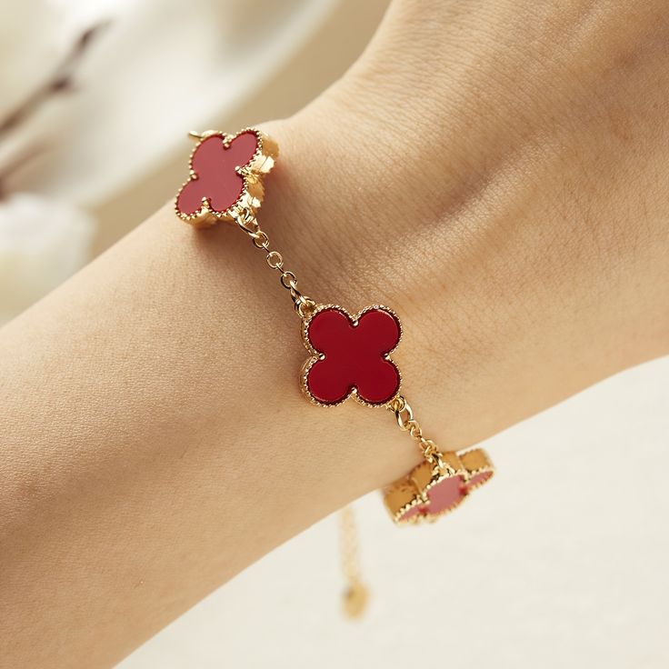 Pulsera de trébol con dijes rojos en la muñeca de una mujer