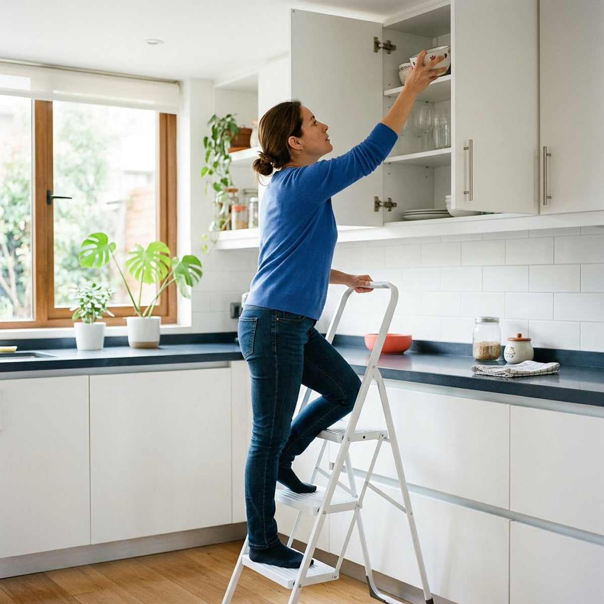 Persona usando la escalera plegable de 4 niveles para alcanzar un estante alto en casa